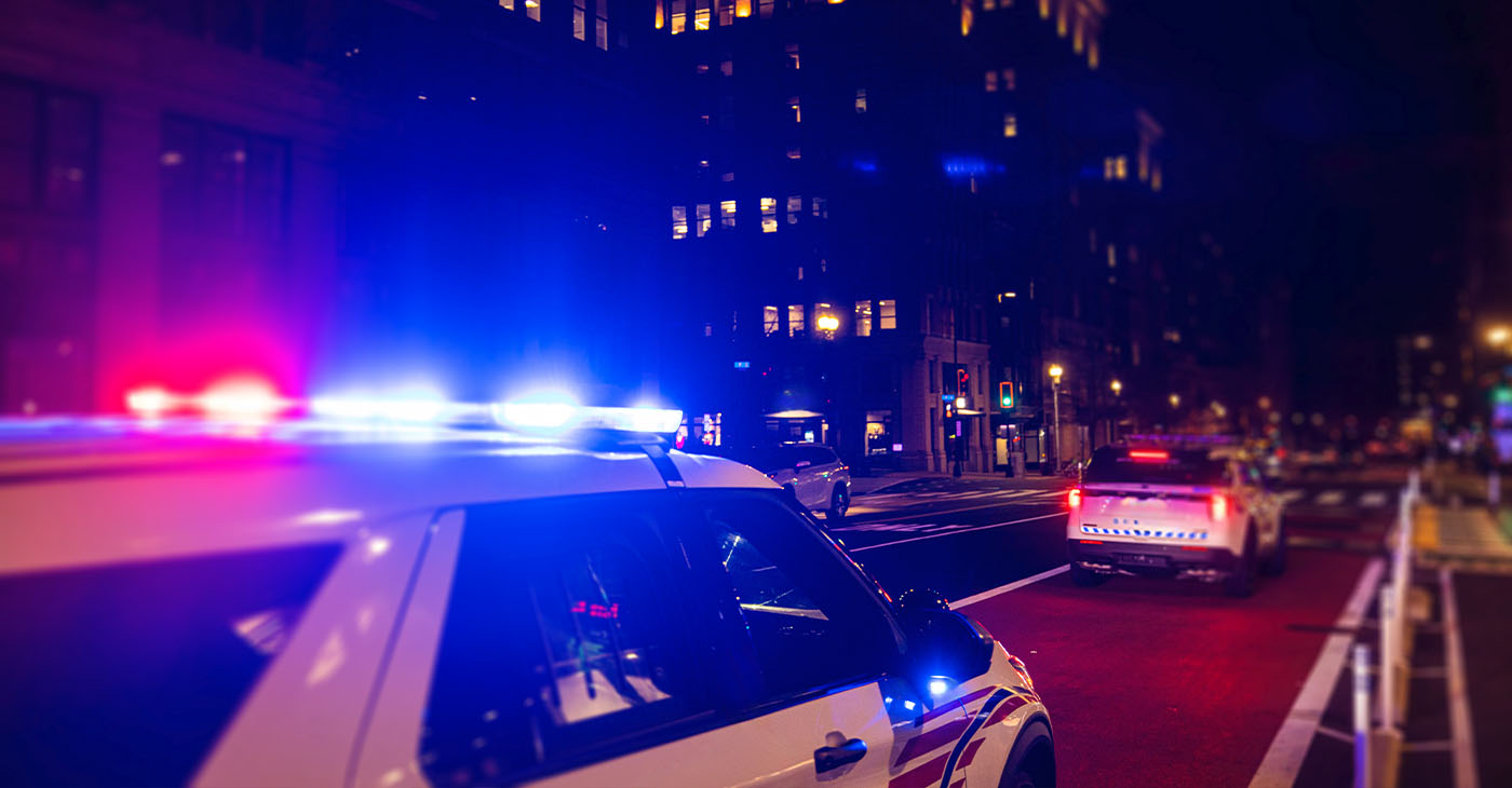 Police Car with Lights on at night in City.