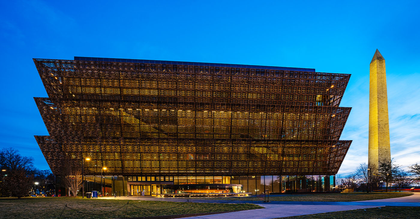 Washington D.C., USA - February 10, 2023: The National Museum of African American History and Culture at night with the Washington Monument in downtown Washington DC.