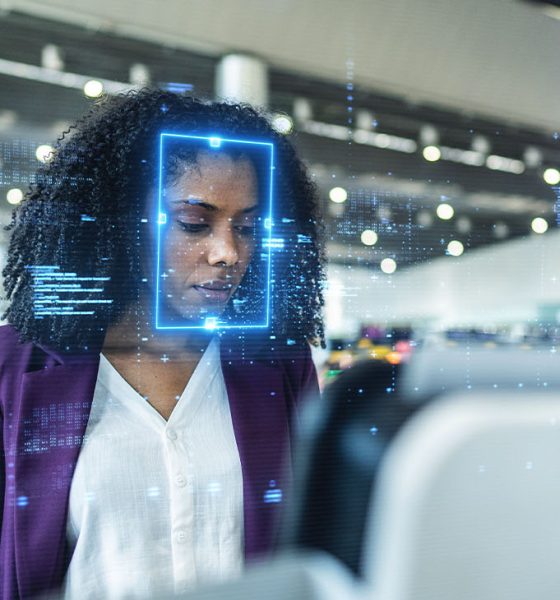 Focused young businesswoman standing at an airport check-in kiosk, with facial recognition technology digitally scanning her face, highlighting advanced security, innovation, and efficiency in modern travel.Focused young businesswoman standing at an airport check-in kiosk, with facial recognition technology digitally scanning her face, highlighting advanced security, innovation, and efficiency in modern travel.