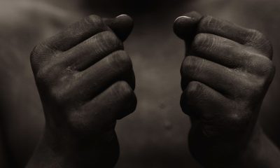 Black person with wearing black paint, holding fist in front of chest in sign of freedom and power.