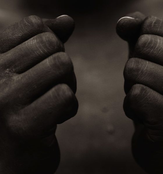 Black person with wearing black paint, holding fist in front of chest in sign of freedom and power.