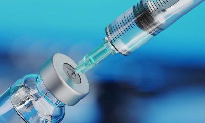 Medical disposable syringe for vaccine injection and glass vial on blue blur background.