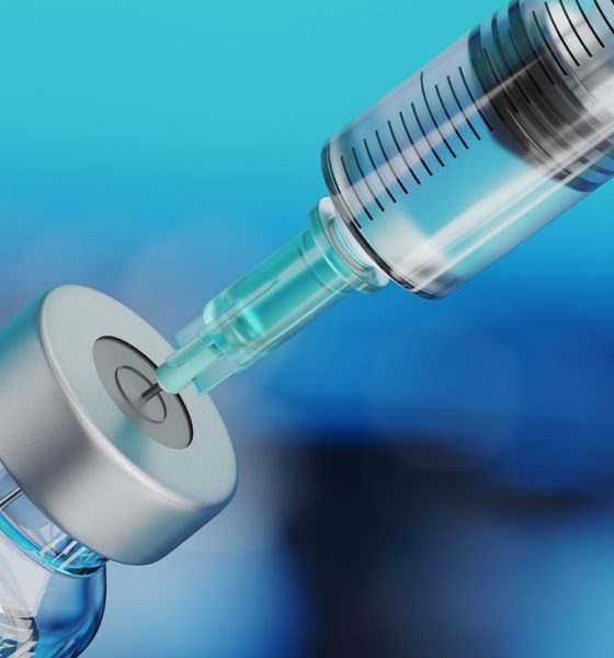 Medical disposable syringe for vaccine injection and glass vial on blue blur background.