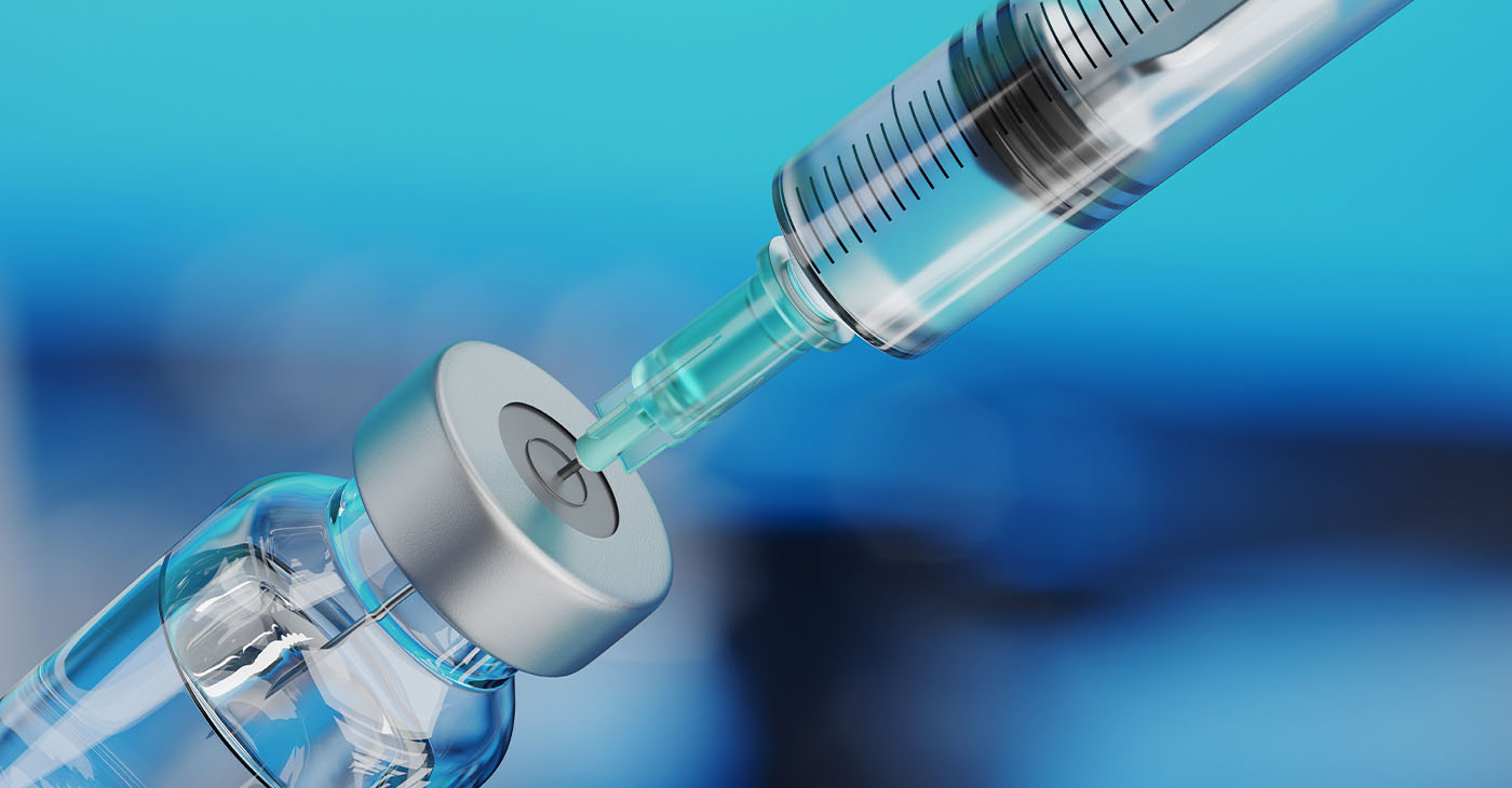 Medical disposable syringe for vaccine injection and glass vial on blue blur background.