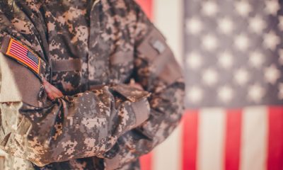Man, dressed in USA army uniform, posing in front of an American flag