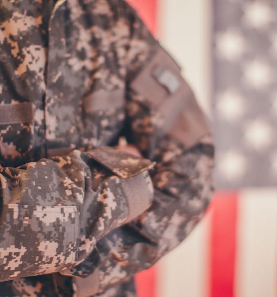 Man, dressed in USA army uniform, posing in front of an American flag