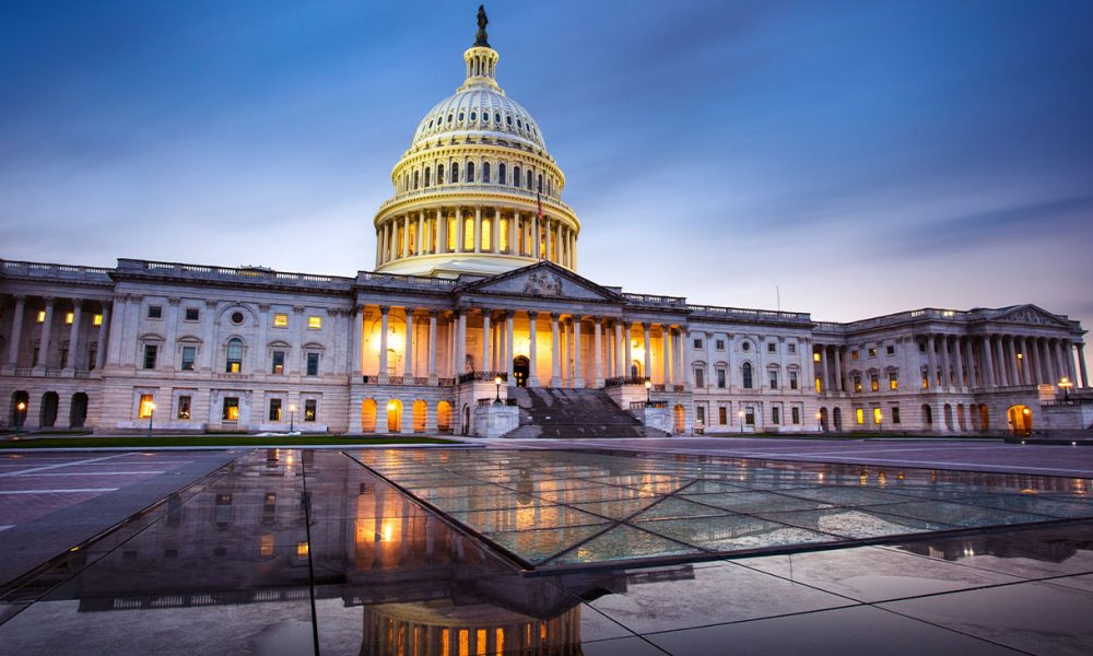 Capitol building in Washington DC illuminated against a stormy sky