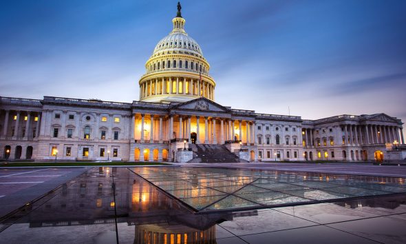 Capitol building in Washington DC illuminated against a stormy sky