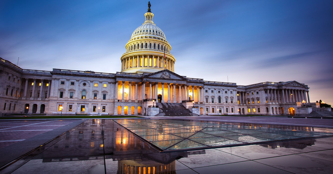 Capitol building in Washington DC illuminated against a stormy sky