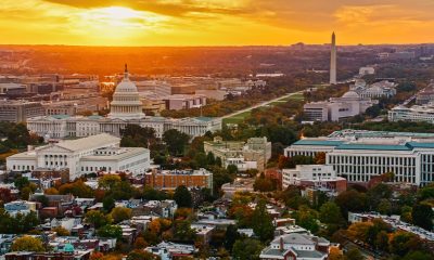 Helicopter shot of Capitol Hill in Washington, D.C. at sunset on a fall evening, looking over residential streets towards the U.S. Capitol Building, Supreme Court, and the National Mall.