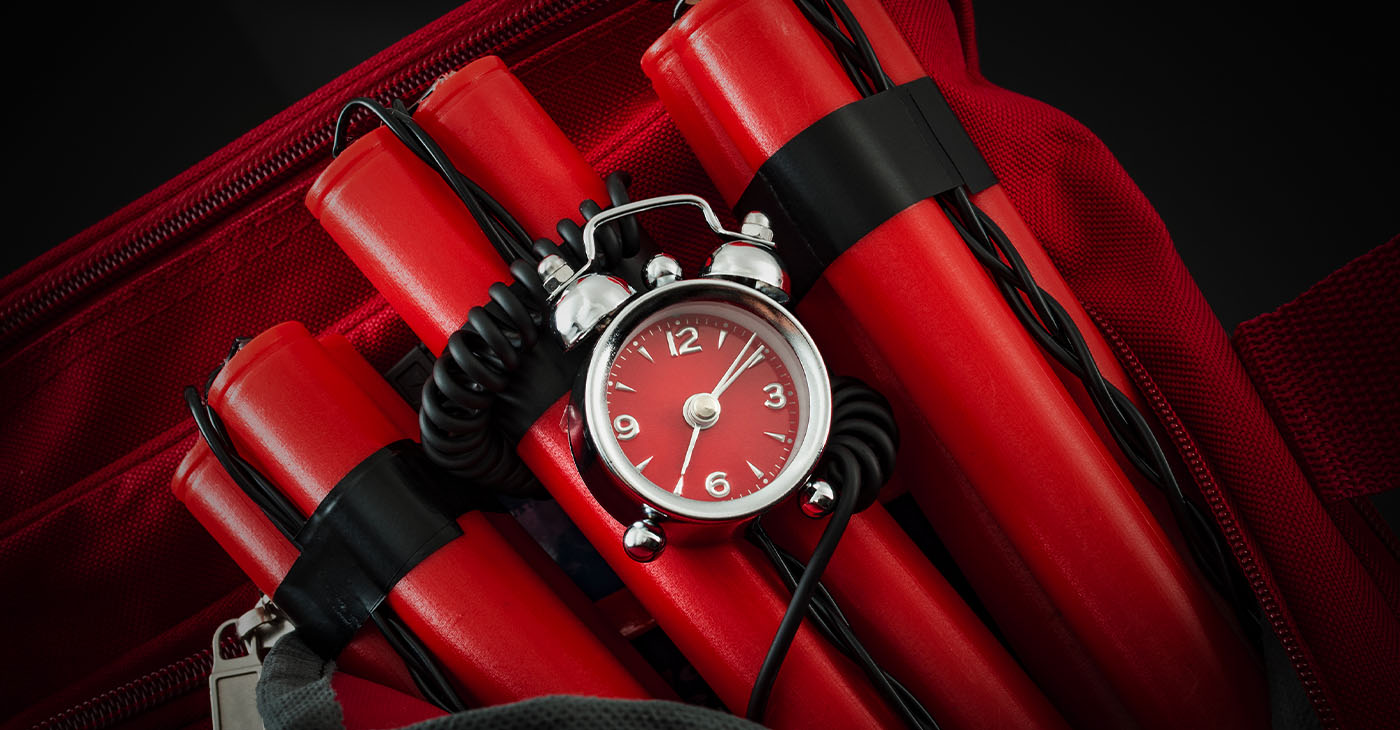 Terrorism and bomb threat concept with dynamite or TNT stick, alarm clock, black wires and a red duffle bag with dark dramatic lighting