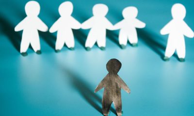 Racism concept image. White paper person agains black paper person (Photo by Liia Galimzianova)