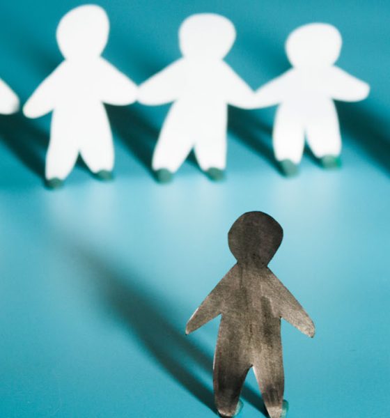 Racism concept image. White paper person agains black paper person (Photo by Liia Galimzianova)
