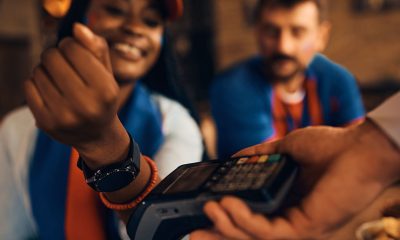 Close up of a woman paying contactless with smart watch during sports championship in a bar. (Photo by Drazen Zigic)