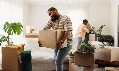 Box, phone call and real estate with black couple moving in to new home for relocation or update. Carry, conversation and property with people in apartment for mobile discussion, packing or planning (Photo by Jacob Wackerhausen)