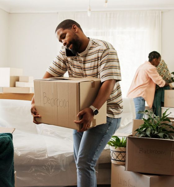 Box, phone call and real estate with black couple moving in to new home for relocation or update. Carry, conversation and property with people in apartment for mobile discussion, packing or planning (Photo by Jacob Wackerhausen)