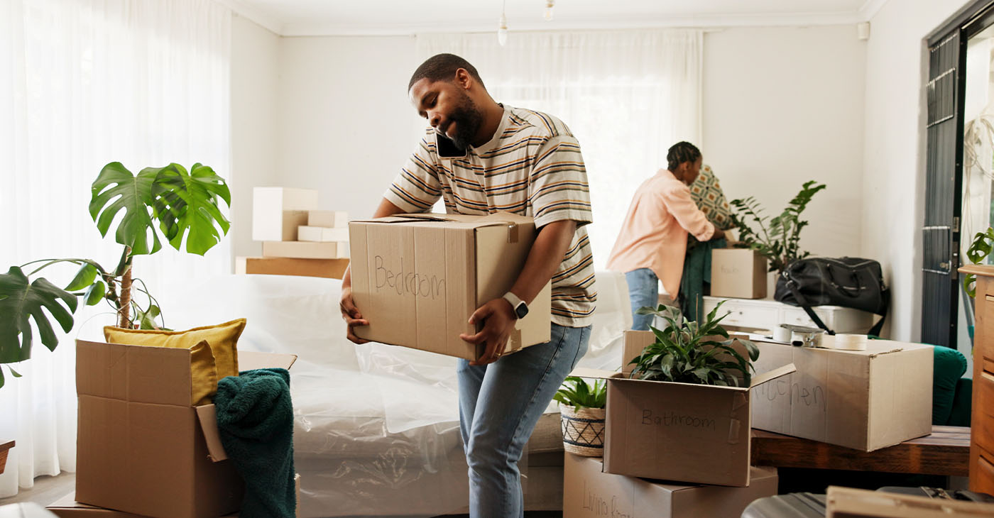 Box, phone call and real estate with black couple moving in to new home for relocation or update. Carry, conversation and property with people in apartment for mobile discussion, packing or planning (Photo by Jacob Wackerhausen)