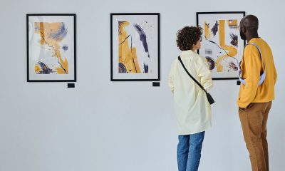 Rear view of young couple visiting art gallery, they standing and watching modern art