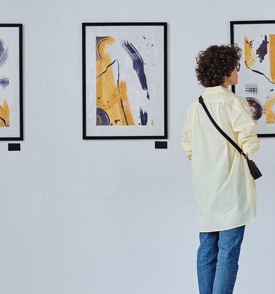 Rear view of young couple visiting art gallery, they standing and watching modern art
