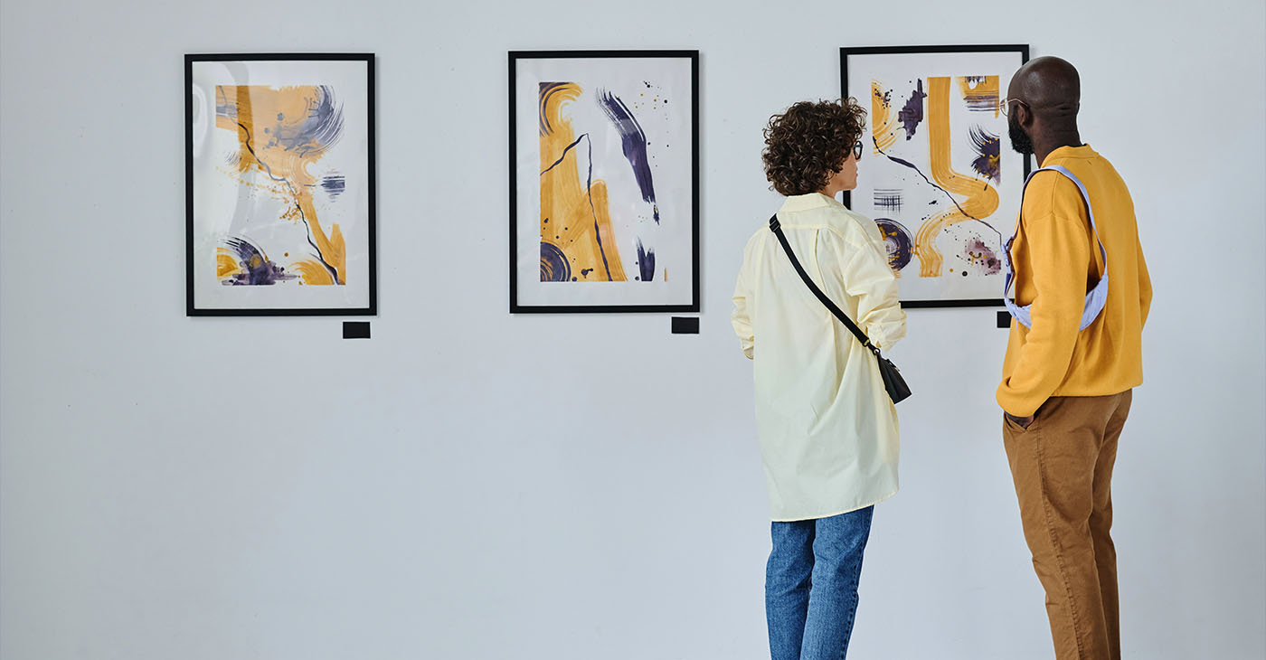 Rear view of young couple visiting art gallery, they standing and watching modern art