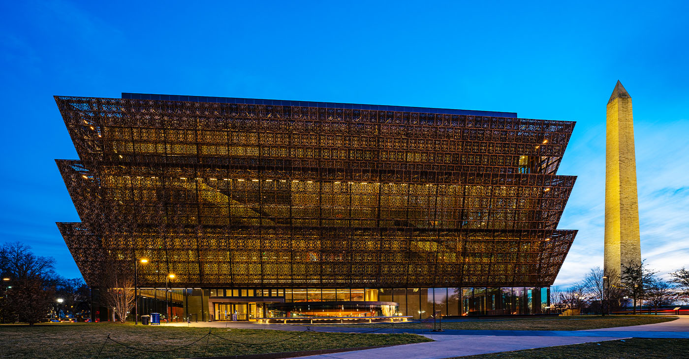 Washington D.C., USA - February 10, 2023: The National Museum of African American History and Culture at night with the Washington Monument in downtown Washington DC.