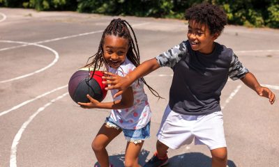 Brother and sister playing basketball and having fun outdoors.