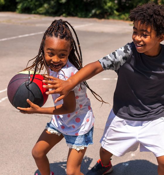 Brother and sister playing basketball and having fun outdoors.
