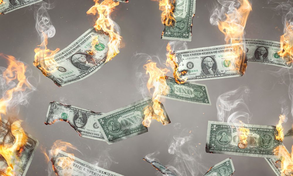 US dollar banknotes on fire are falling down. Isolated on neutral background.