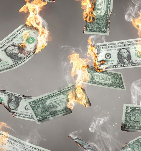 US dollar banknotes on fire are falling down. Isolated on neutral background.