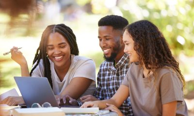 Students, friends and group studying with laptop at park outdoors. Education scholarship, learning teamwork and happy people, black man and women with computer for research at university or college.