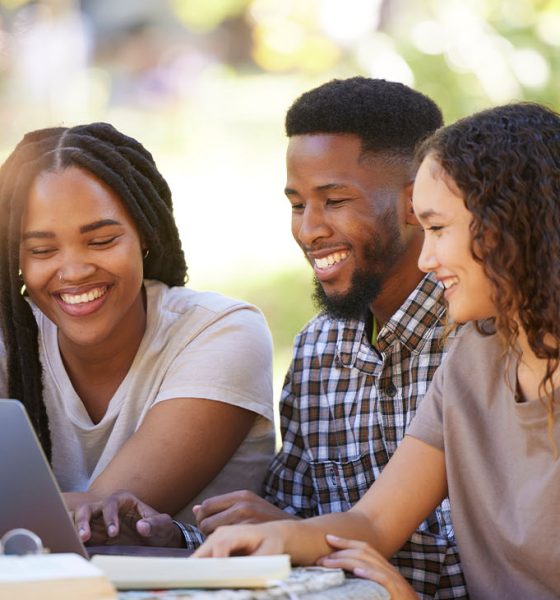 Students, friends and group studying with laptop at park outdoors. Education scholarship, learning teamwork and happy people, black man and women with computer for research at university or college.