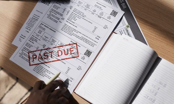 Top view closeup of unrecognizable man doing taxes at home with past due bill on table, copy space