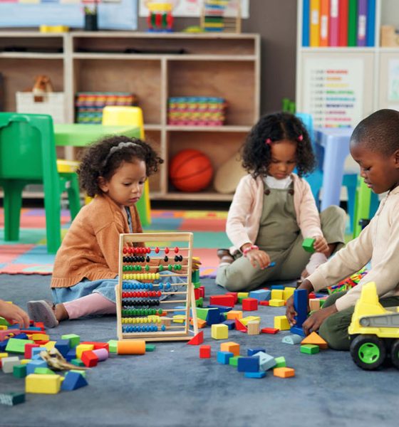 Kids, students and play with blocks in classroom for learning, problem solving and creative activity. Children, toys and floor for education game, puzzle solution and motor growth in kindergarten 