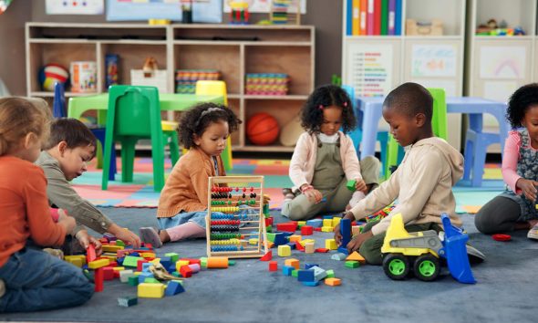 Kids, students and play with blocks in classroom for learning, problem solving and creative activity. Children, toys and floor for education game, puzzle solution and motor growth in kindergarten 