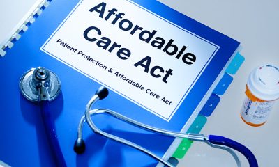 Still life of a manual handbook for the Patient Protection and Affordable Care Act with a stethoscope and prescription medication bottle. The manual is open to the title page, The open enrollment of the Affordable Care Act of the United States offers a health insurance program for all the U.S. citizens across the country.