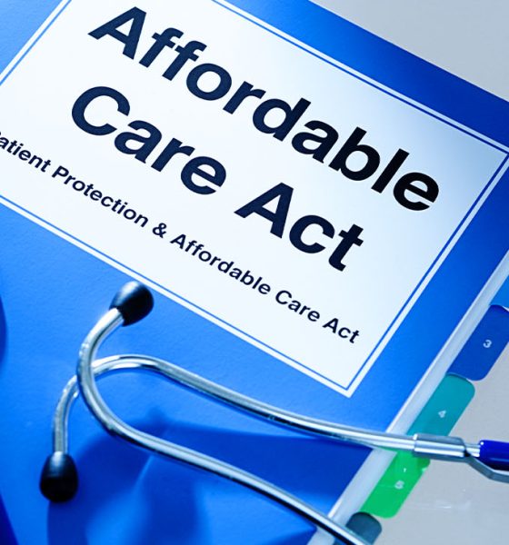 Still life of a manual handbook for the Patient Protection and Affordable Care Act with a stethoscope and prescription medication bottle. The manual is open to the title page, The open enrollment of the Affordable Care Act of the United States offers a health insurance program for all the U.S. citizens across the country.