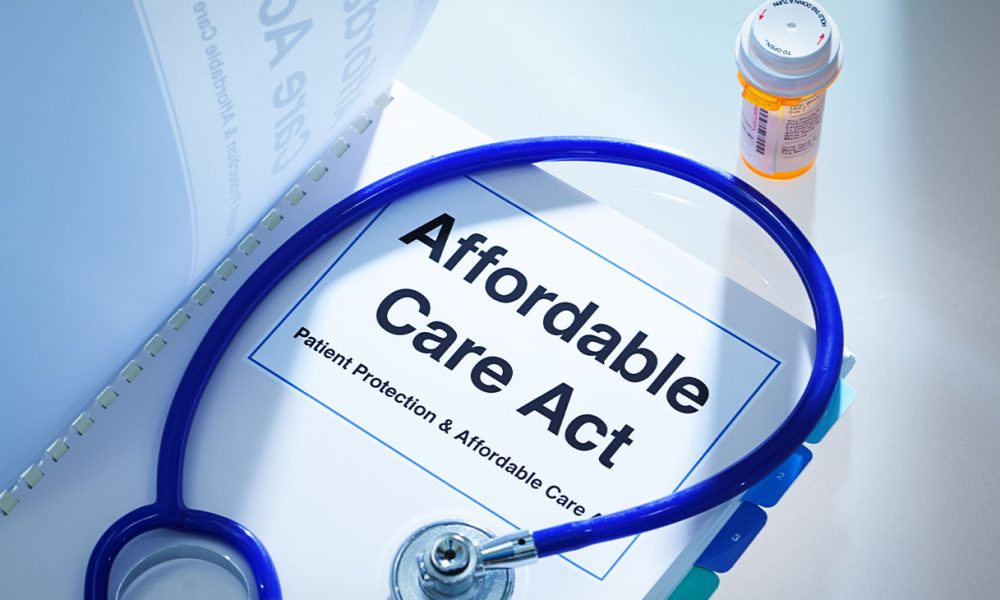 Still life of a manual handbook for the Patient Protection and Affordable Care Act with a stethoscope and prescription medication bottle. The manual is open to the title page, The open enrollment of the Affordable Care Act of the United States offers a health insurance program for all the U.S. citizens across the country.