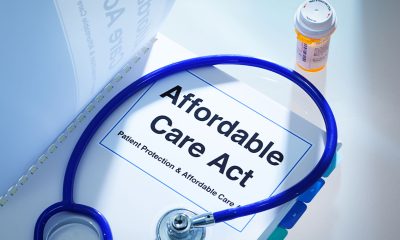 Still life of a manual handbook for the Patient Protection and Affordable Care Act with a stethoscope and prescription medication bottle. The manual is open to the title page, The open enrollment of the Affordable Care Act of the United States offers a health insurance program for all the U.S. citizens across the country.