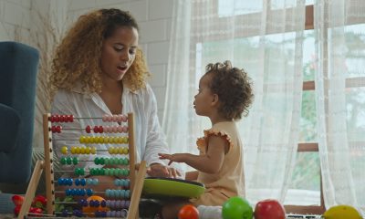 Mother and daughter are doing play a toy and having fun in living room.