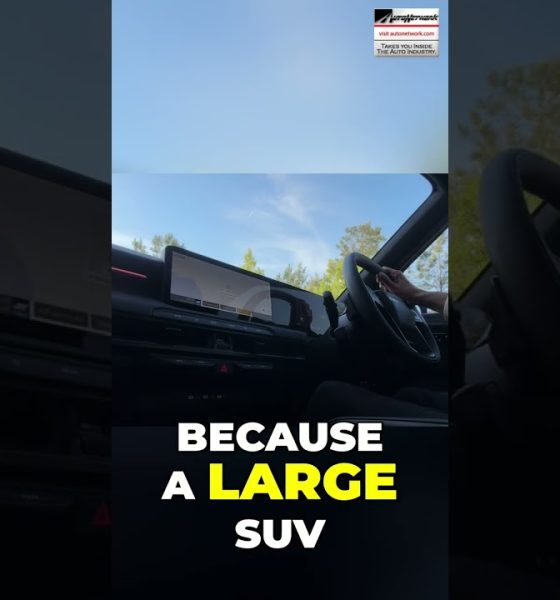 Interior of a car cabin with a large touchscreen/dashboard visible and bold text overlay: 'BECAUSE A LARGE SUV' in white and yellow.