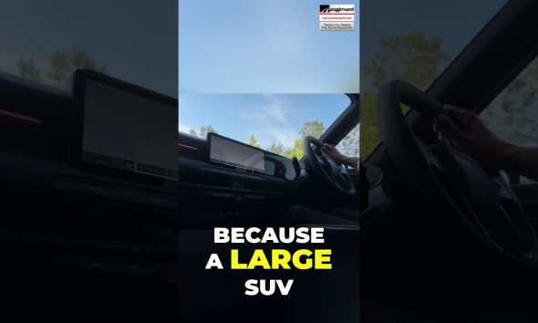 Interior of a car cabin with a large touchscreen/dashboard visible and bold text overlay: 'BECAUSE A LARGE SUV' in white and yellow.