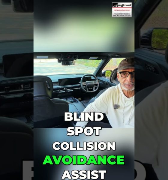 Man wearing a cap and glasses sits in a car interior with bold white text about blind-spot collision avoidance.