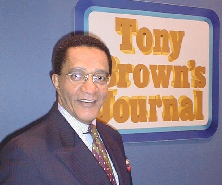 Tony Brown poses in front of the Tony Brown's Journal logo. Brown, who died June 17 at age 93, transformed Black public affairs television and influenced generations of journalists through his groundbreaking broadcast career.