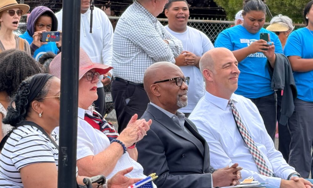 Pastor Michael Wallace of Mt. Zion Missionary Baptist Church (center) and David Kimball, president of the Oakland Stake of the LDS church listen to remarks before volunteers began their work. “We are grateful to partner with these organizations to help care for those in need in our community,” Kimball later told the assembled volunteers. Courtesy photo.