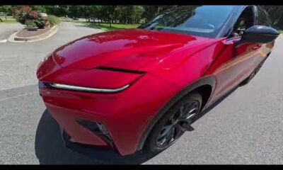 2026 Toyota Crown driving on a paved road, showcasing its sleek design and modern features.