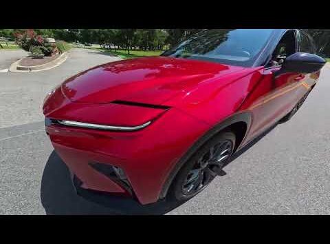 2026 Toyota Crown driving on a paved road, showcasing its sleek design and modern features.