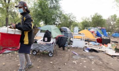 Aug 5, 2026, Saint Paul – A resident of the Pigs Eye encampment carries items out of it. Credit: Chris Juhn