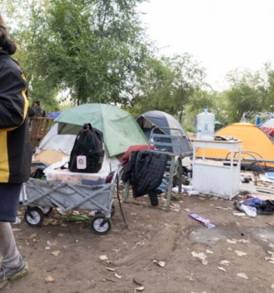 Aug 5, 2026, Saint Paul – A resident of the Pigs Eye encampment carries items out of it. Credit: Chris Juhn