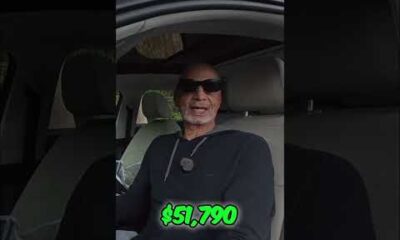 Green dollar bills, symbolizing money, held by a person in a car.