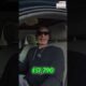 Green dollar bills, symbolizing money, held by a person in a car.